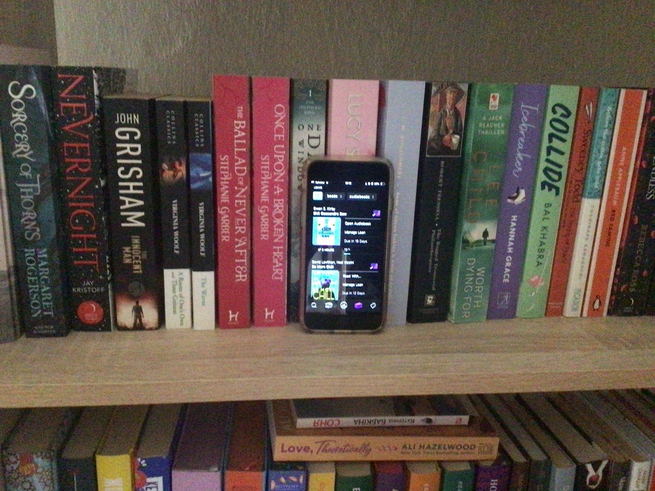 Books on a shelf and smartphone with open Libby app on the screen.